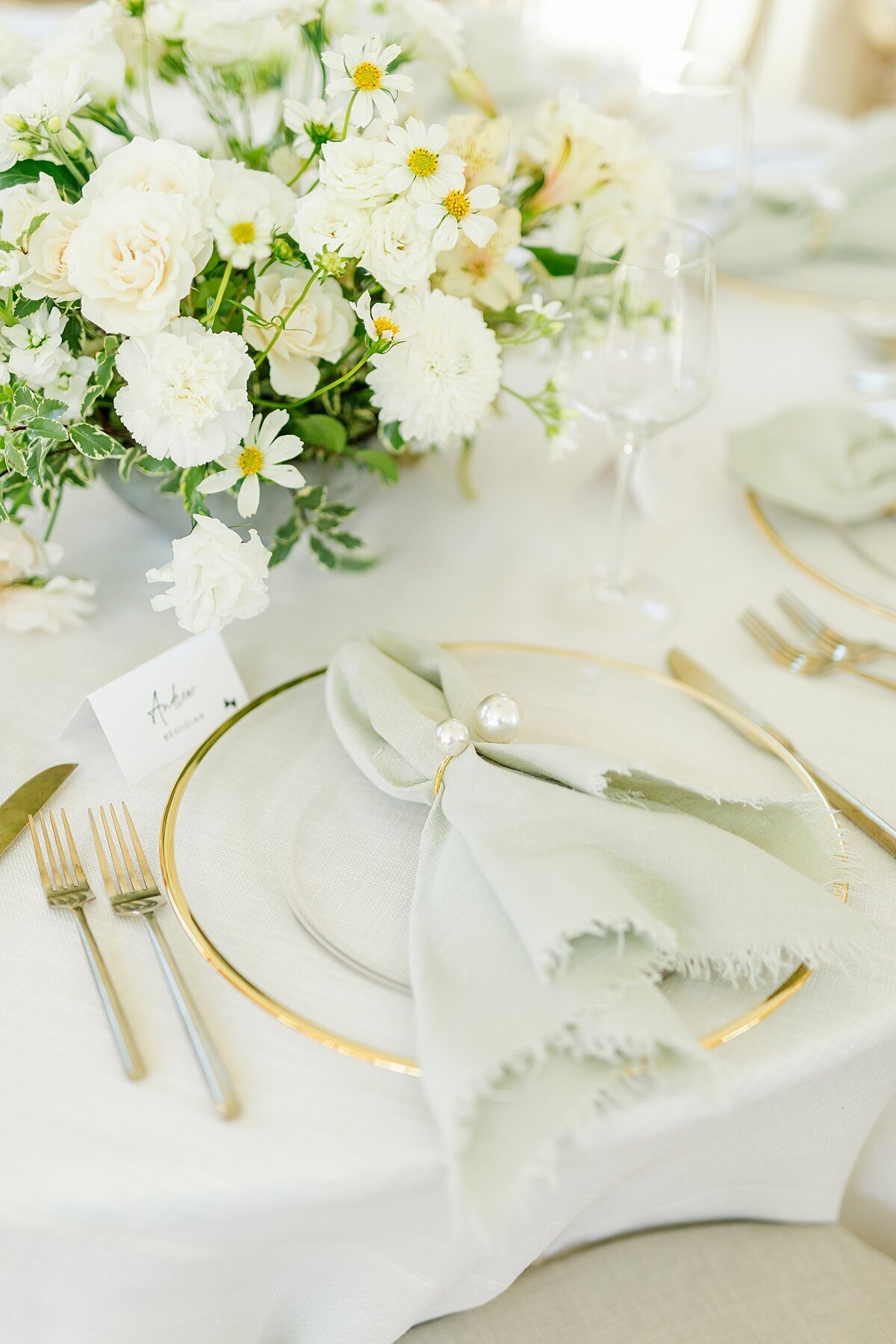 Pearl napkin holder on white linen napkin in front of white and green floral centerpiece inside Monserate Winery in Fallbrook.