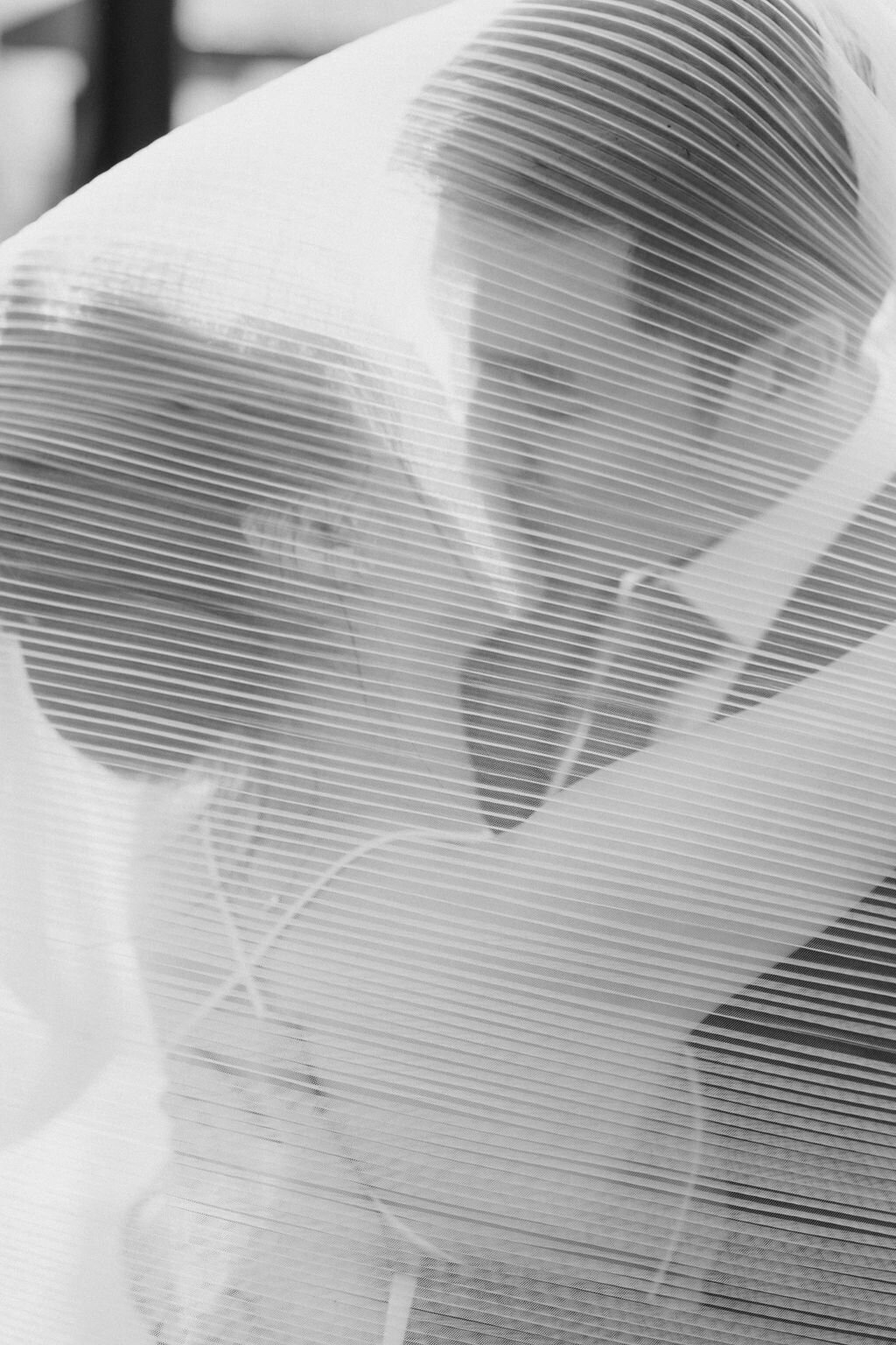 Asian couple kisses underneath bride's veil