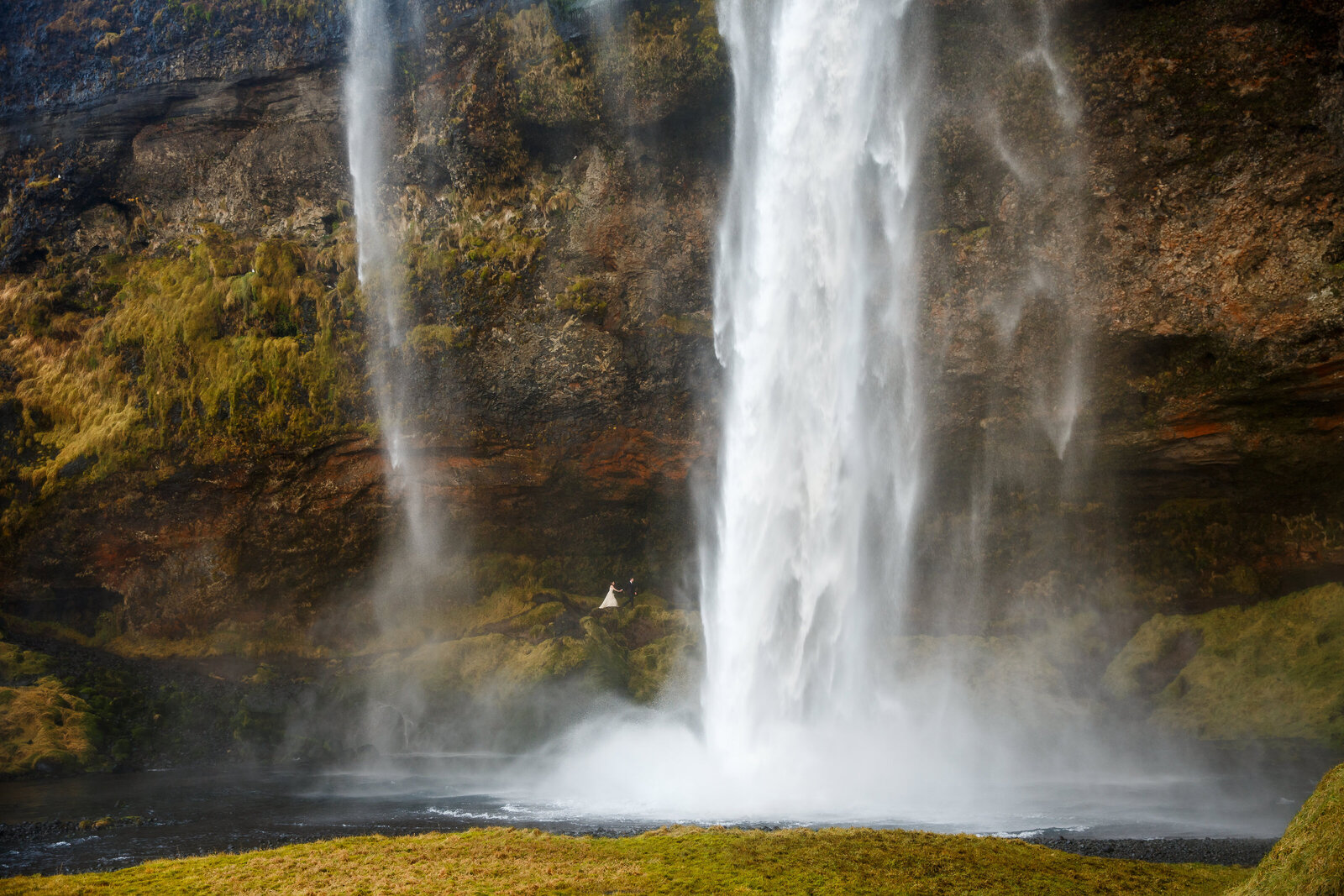 An eloping couple walks behind a huge in Iceland during their elopement.
