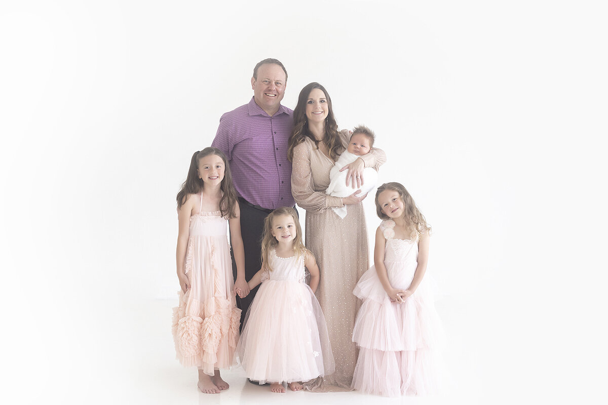 Family admiring newborn baby at photoshoot.