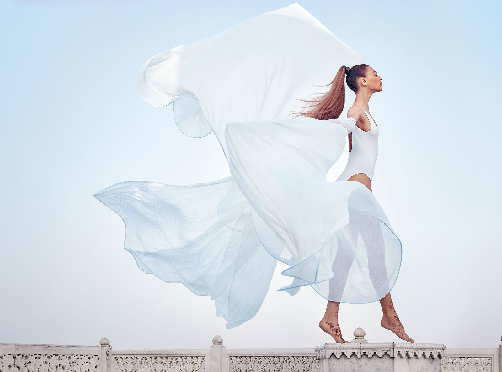 woman with wind blow white shawl against sky background