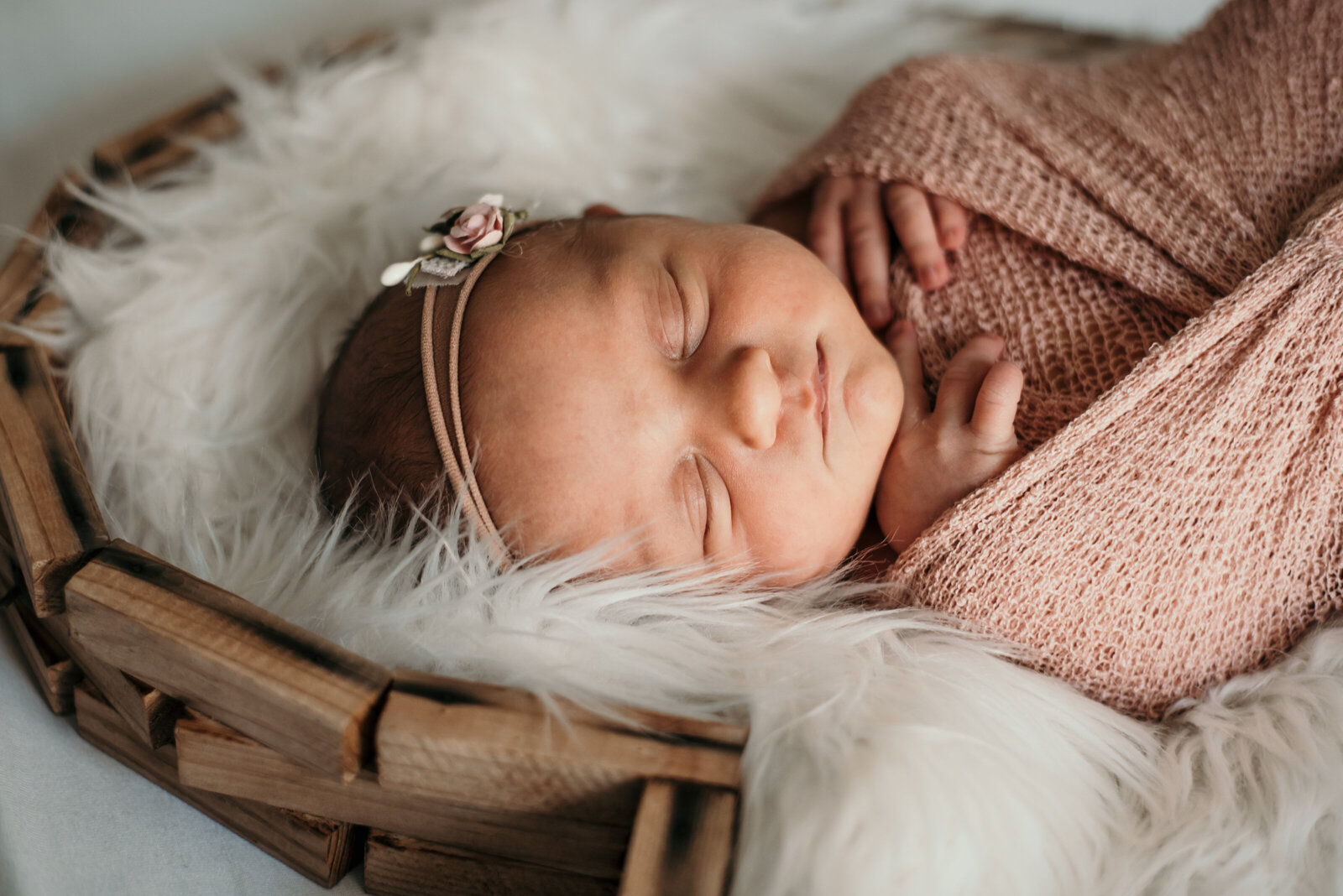 Baby girl with pink mesh wrap and white fur blanket