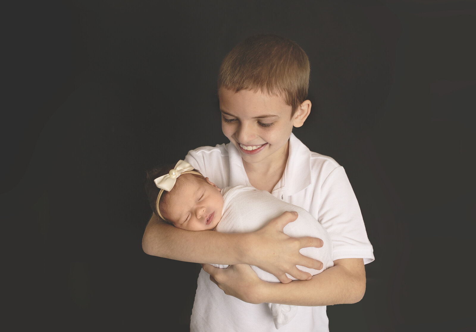 Big brother holding newborn brother during newborn photoshoot with Nashville, TN newborn photographer