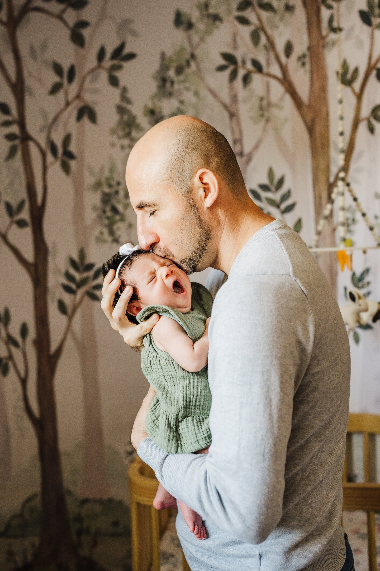 dad holds yawning newborn in jungle themed nursery