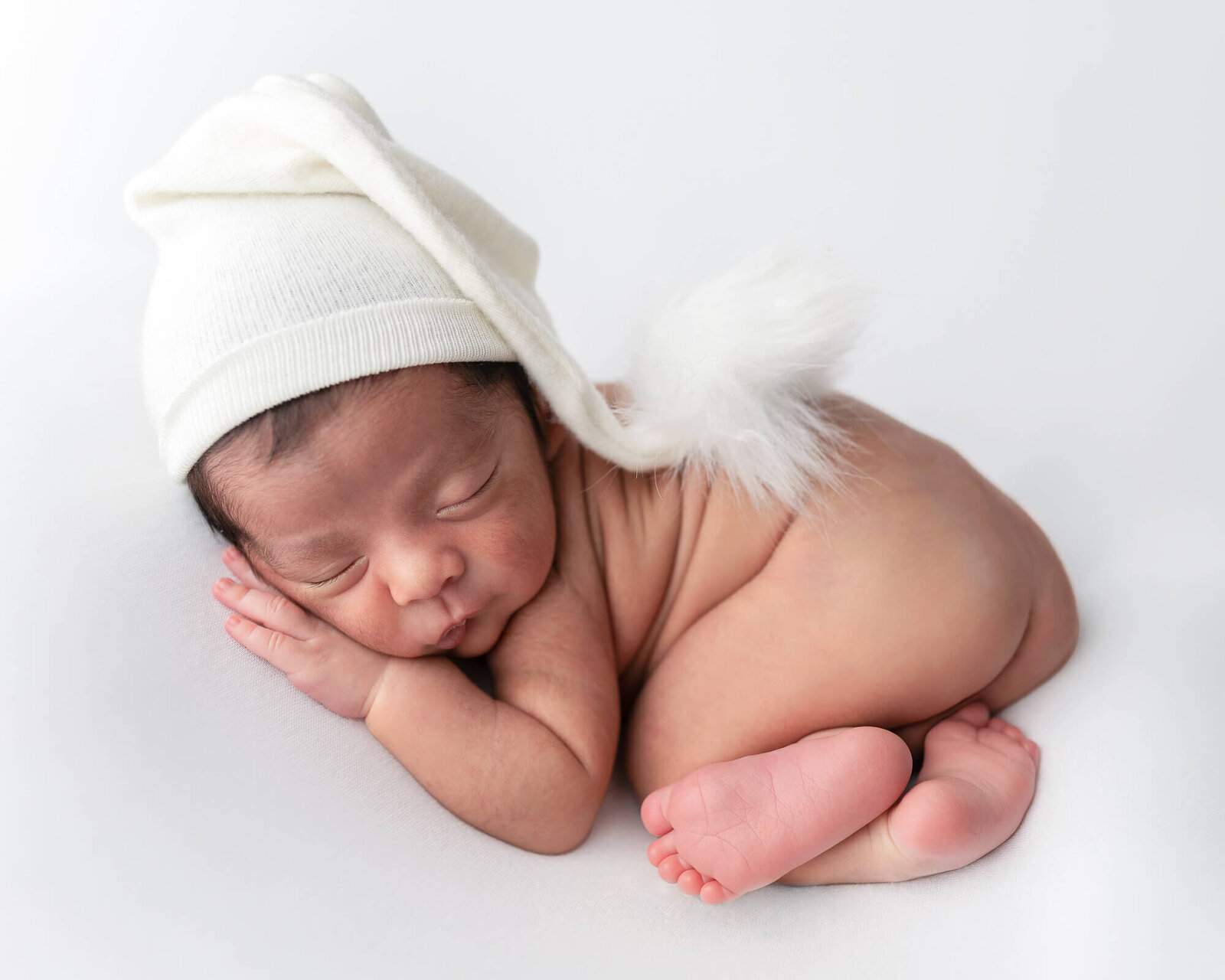 Newborn curled up on white