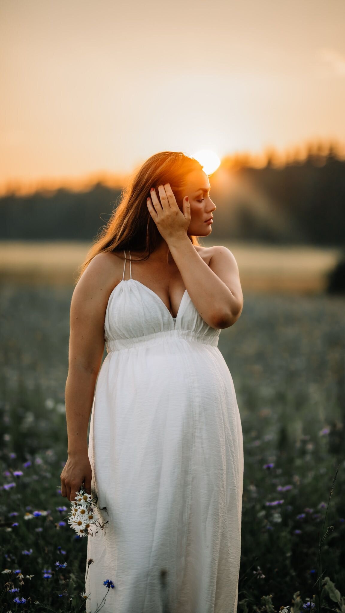 en gravid mamma plockar blommor på ett fält