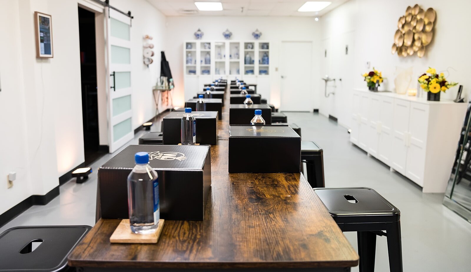 Workshop setup at The Parlor at Wells in Memphis, featuring long wooden tables, black stools, gift boxes, and bottled water—ideal for business events, creative classes, and team gatherings.