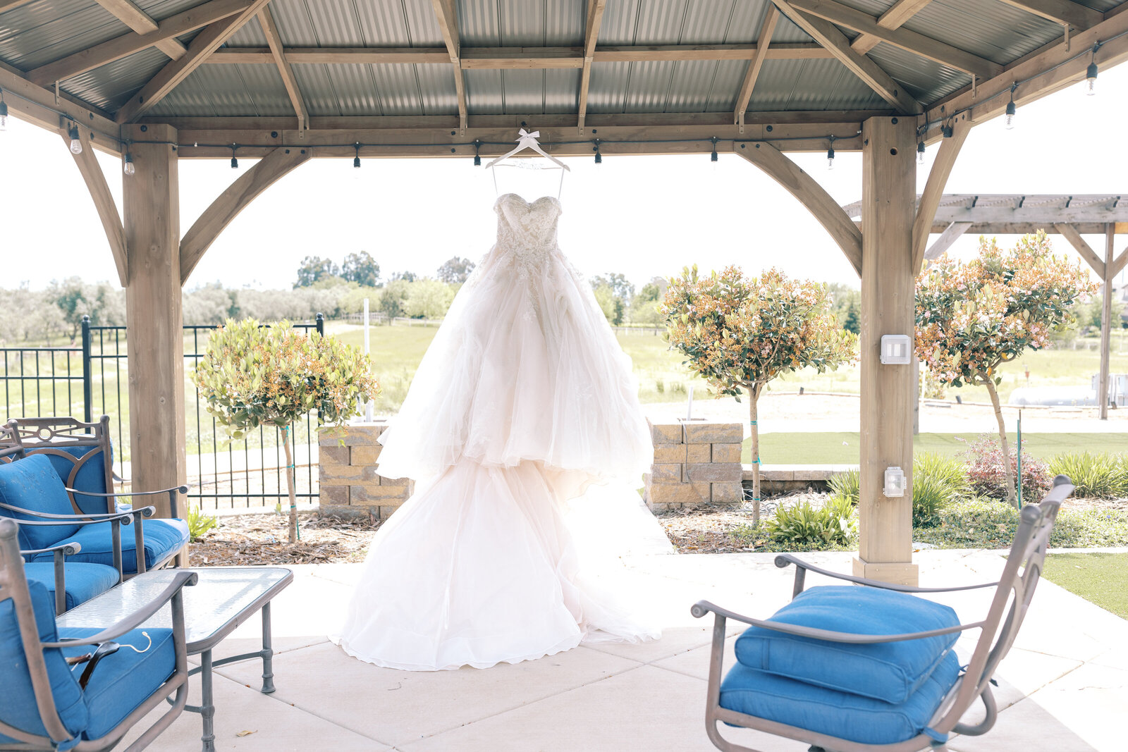 ballroom wedding gown hanging in a pergola for an outdoor wedding picture captured by sacramento wedding photographer at Wolfe Heights