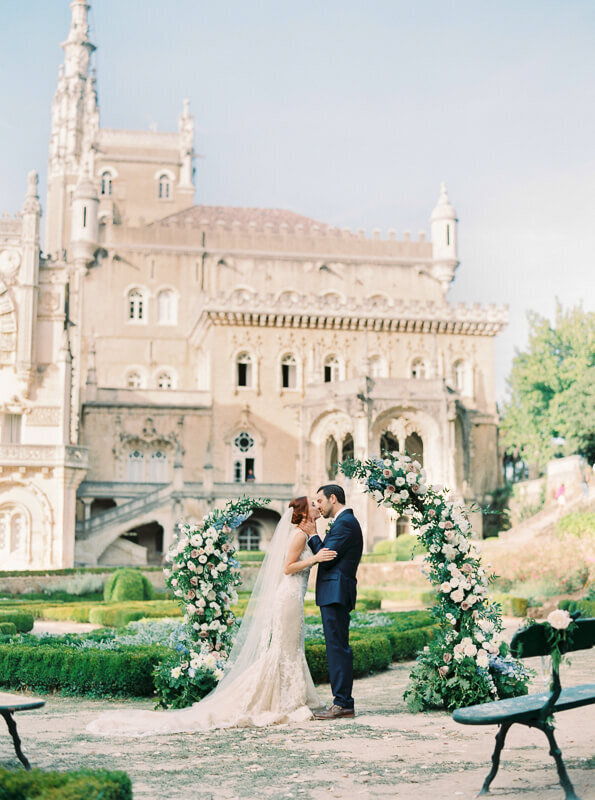 Intimate micro wedding in Portugal at Bussaco Palace with bride and grrom and floral arch  in palace garden  by Splendida Weddings