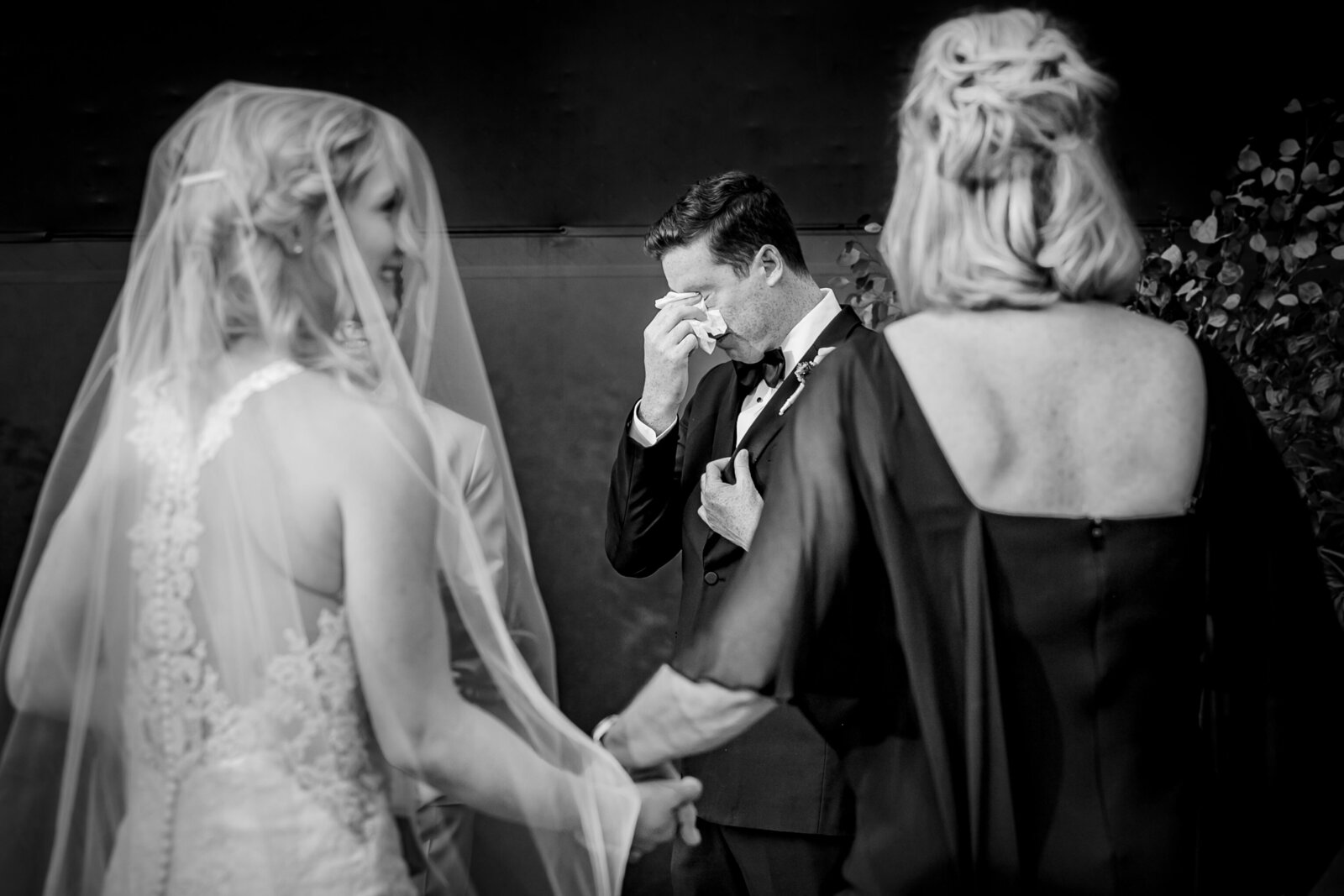 A dashing groom cannot contain his tears during an emotional ceremony as bride is walked down the aisle by her mother in Los Angeles California 