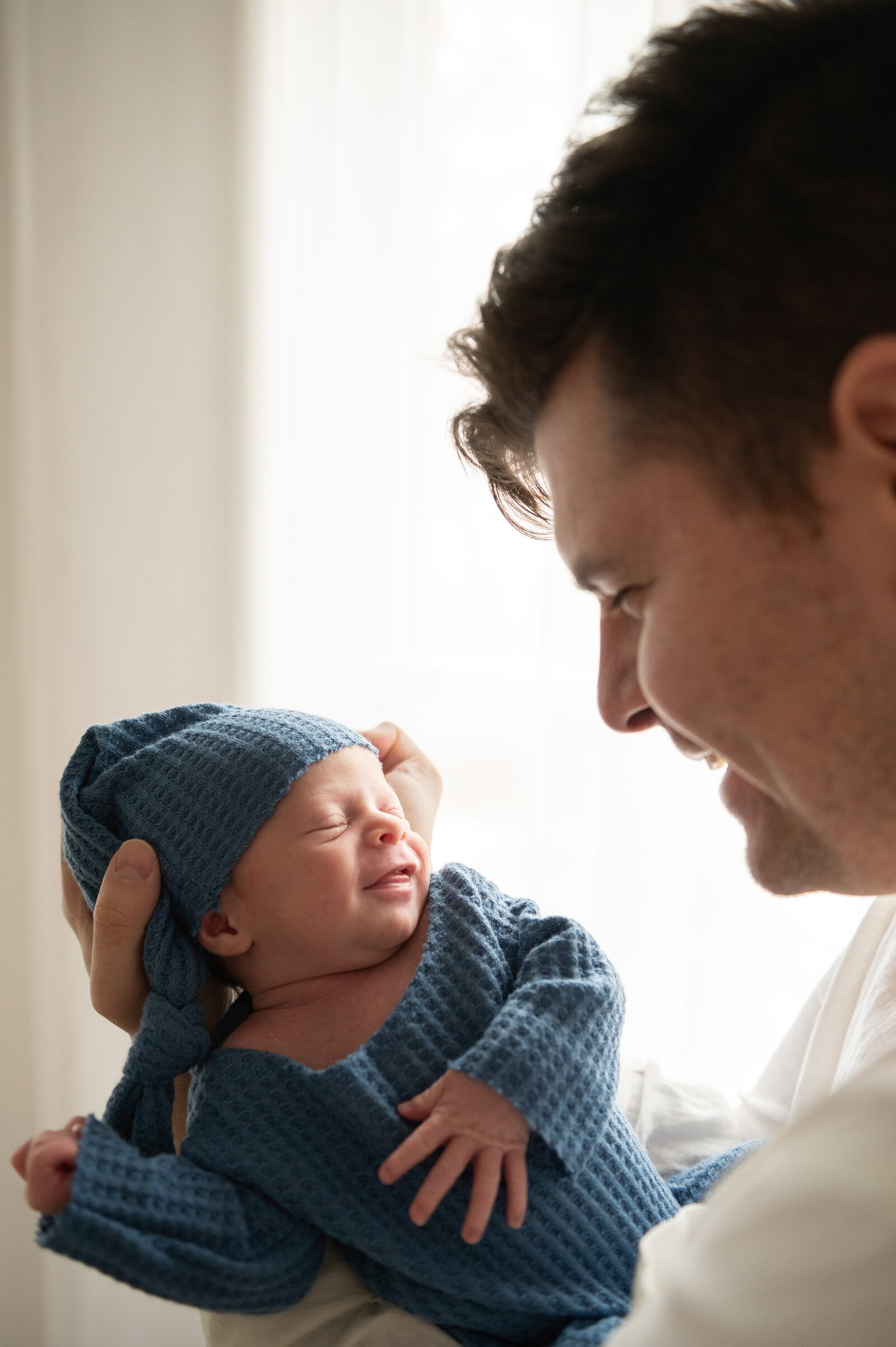 father looking at smiling newborn son