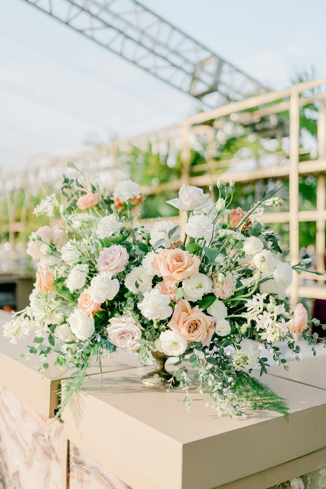 Romantic floral centerpiece with white and blush roses and greenery