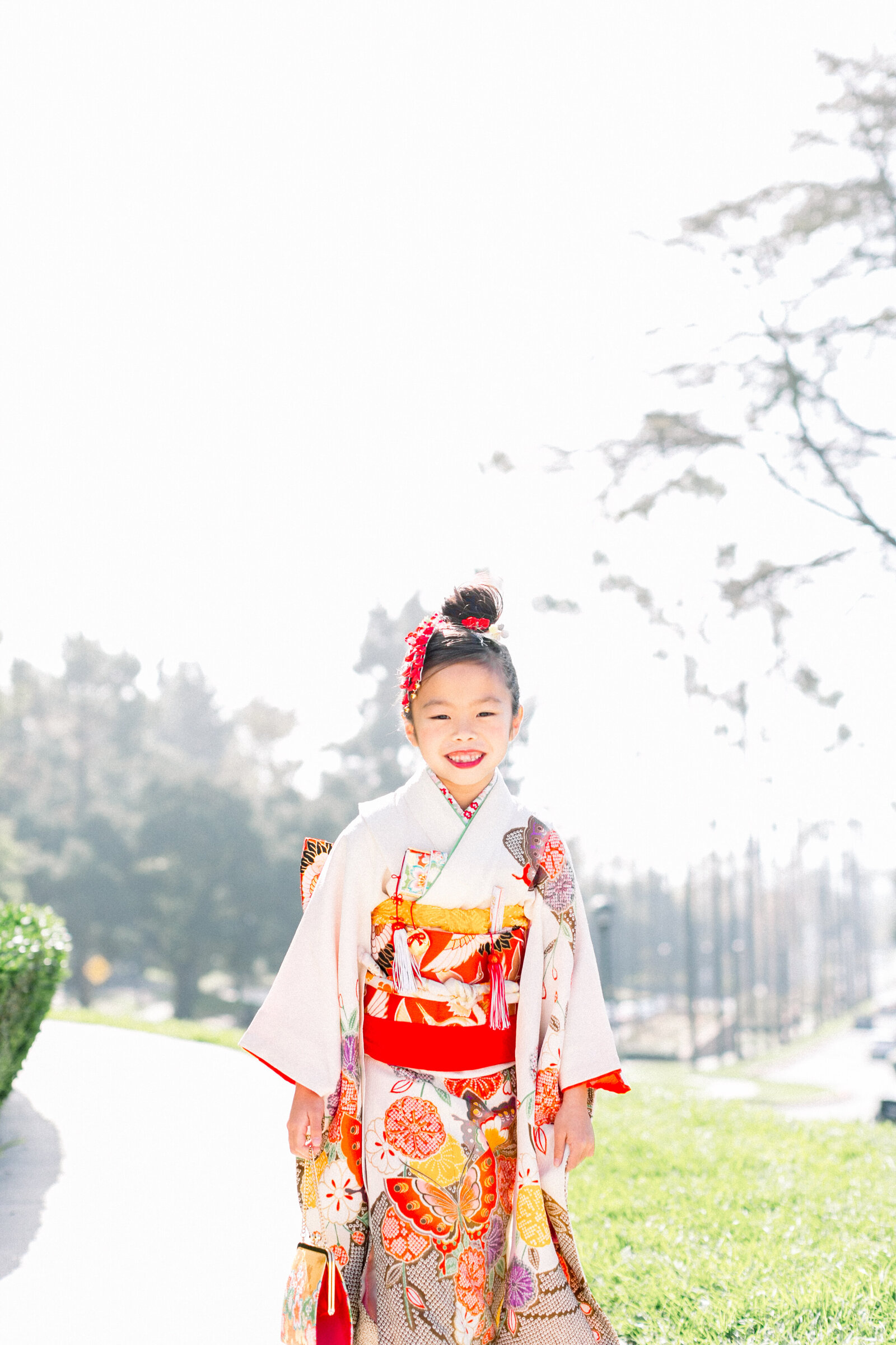 Young girl in a white kimono with colorful patterns posing outdoors for Shichi-Go-San at Brand Park | 七五三 白地の着物を着た女の子 ポートレート ブランド公園