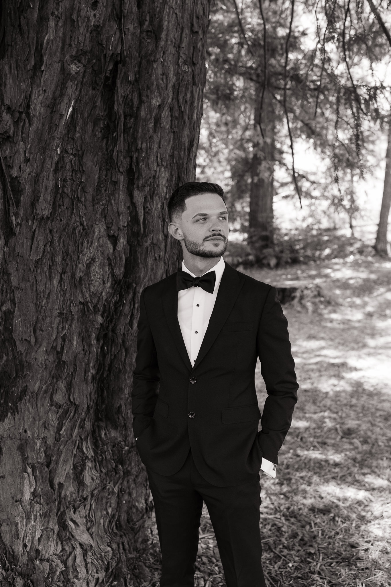 Groom posing under towering redwoods for bridal portraits in Northern California