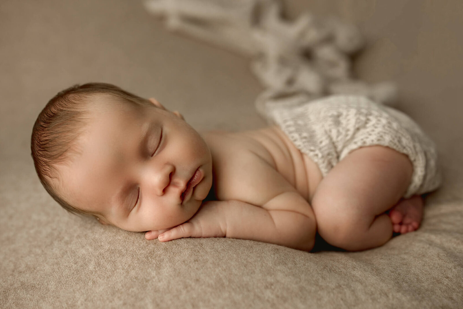 Baby boy with pouty lips sleeping on a tan backdrop in Harrisburg newborn photographer session