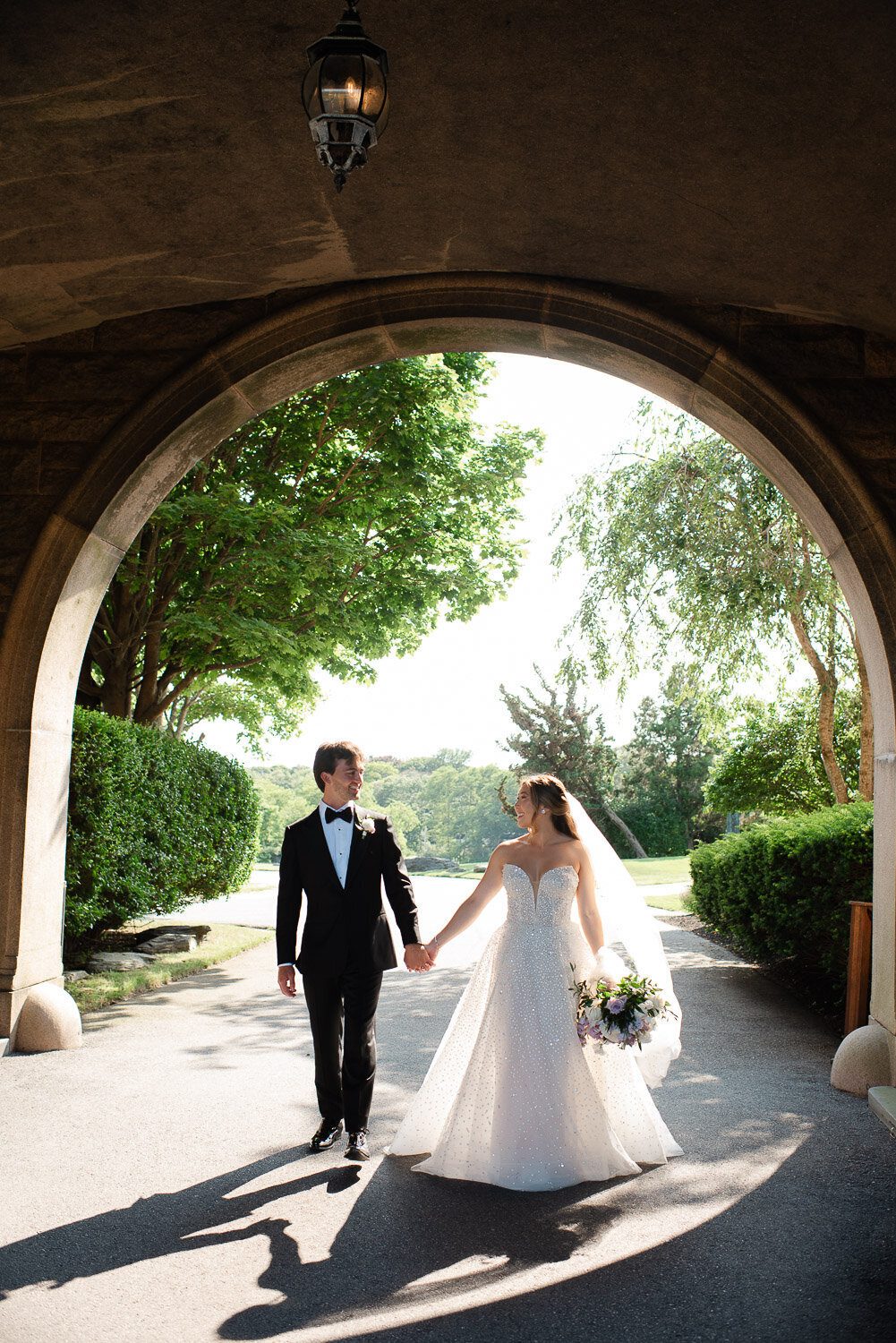 bride and groom holding hand walking through archway