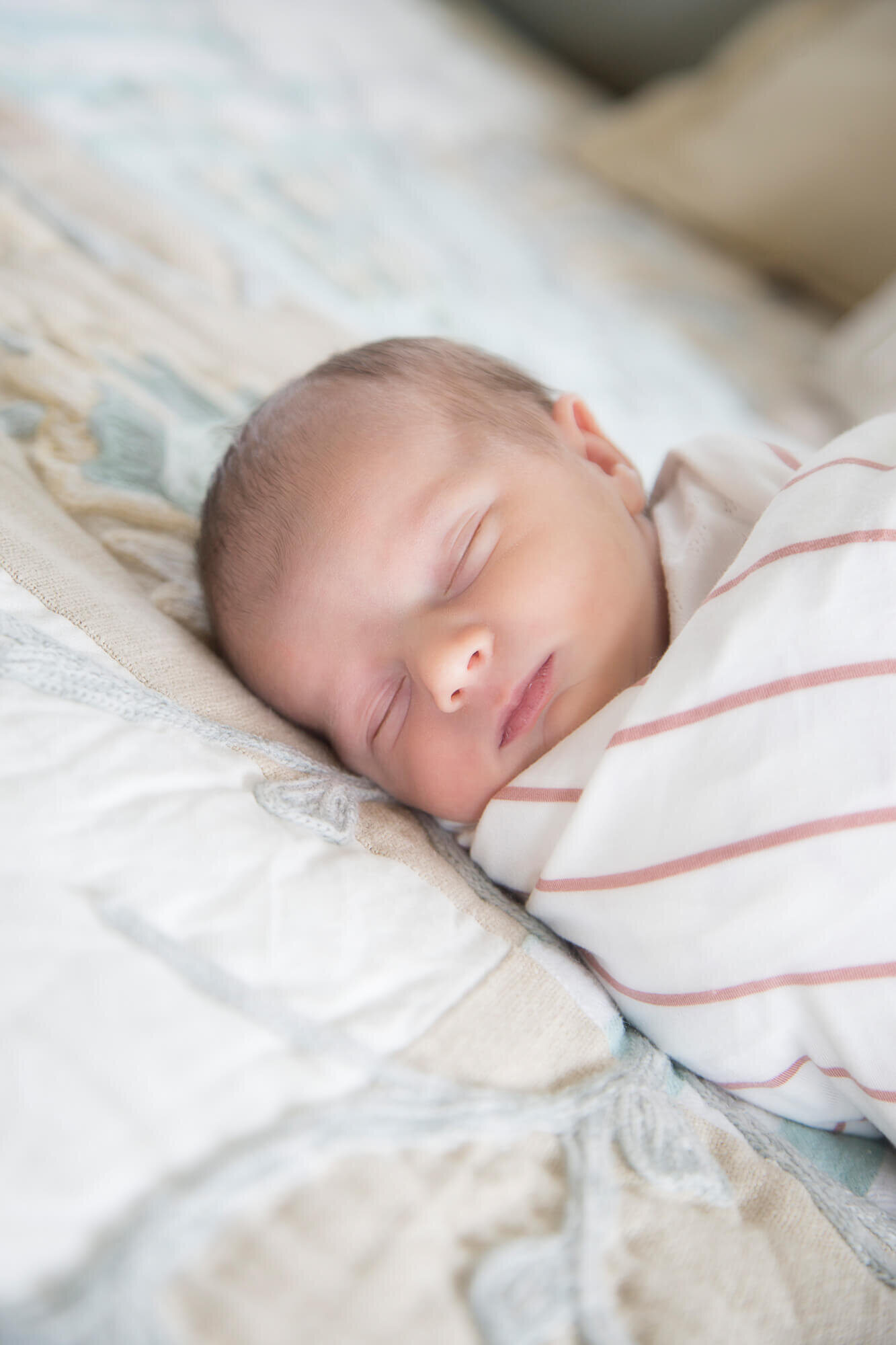 sleeping newborn baby girl on a bed wrapped in a swaddle