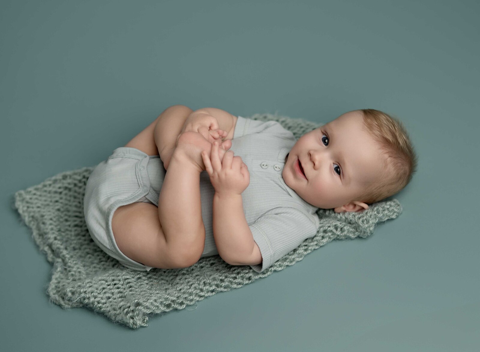 Baby photoshoot of boy laying on back grabbing his toes. Baby milestone photo taken by Jenni Nikki Photography in Atlanta, GA. 