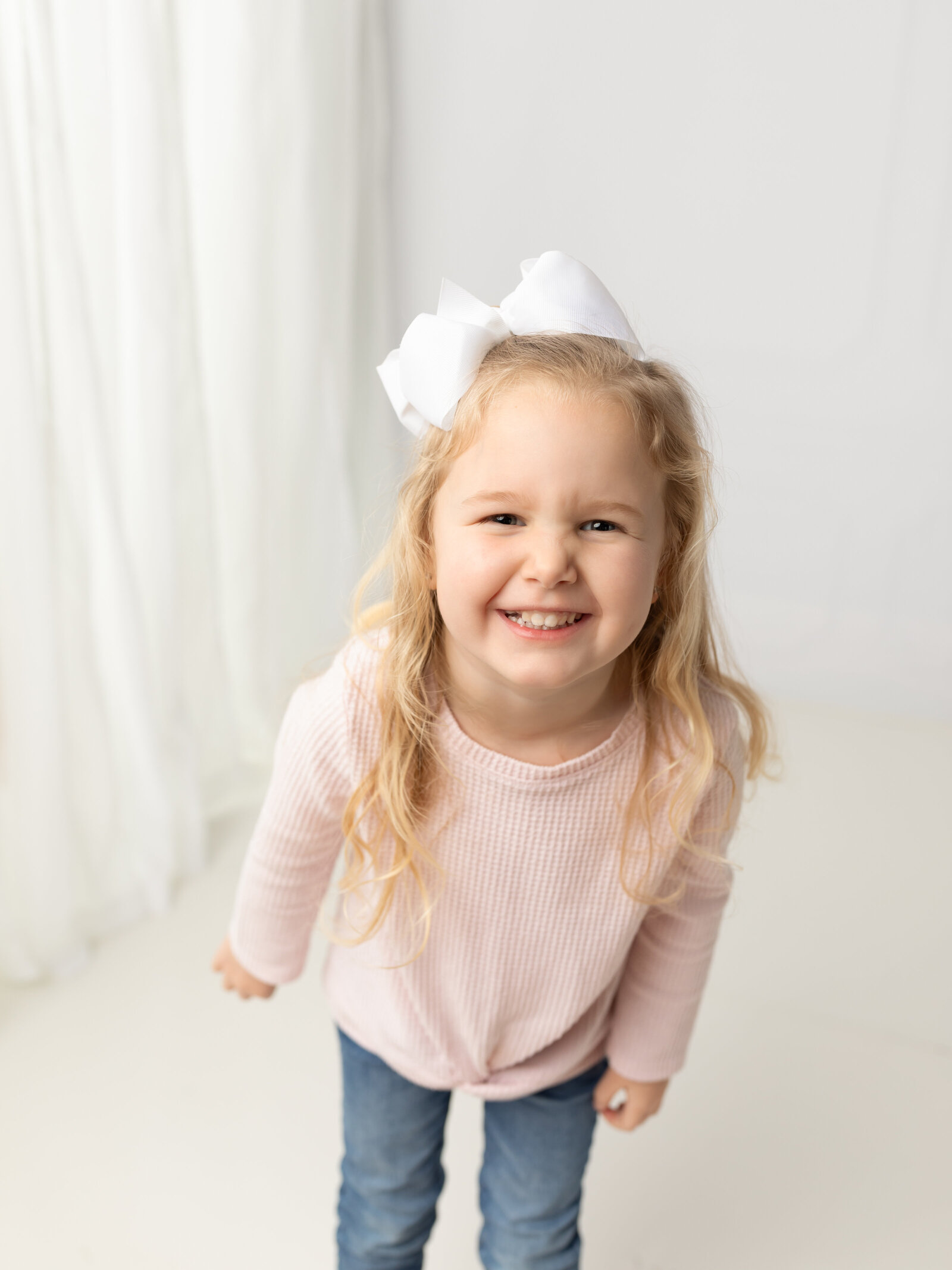 3 year old girl in pink shirt smiling for family photos in studio cleveland family photography