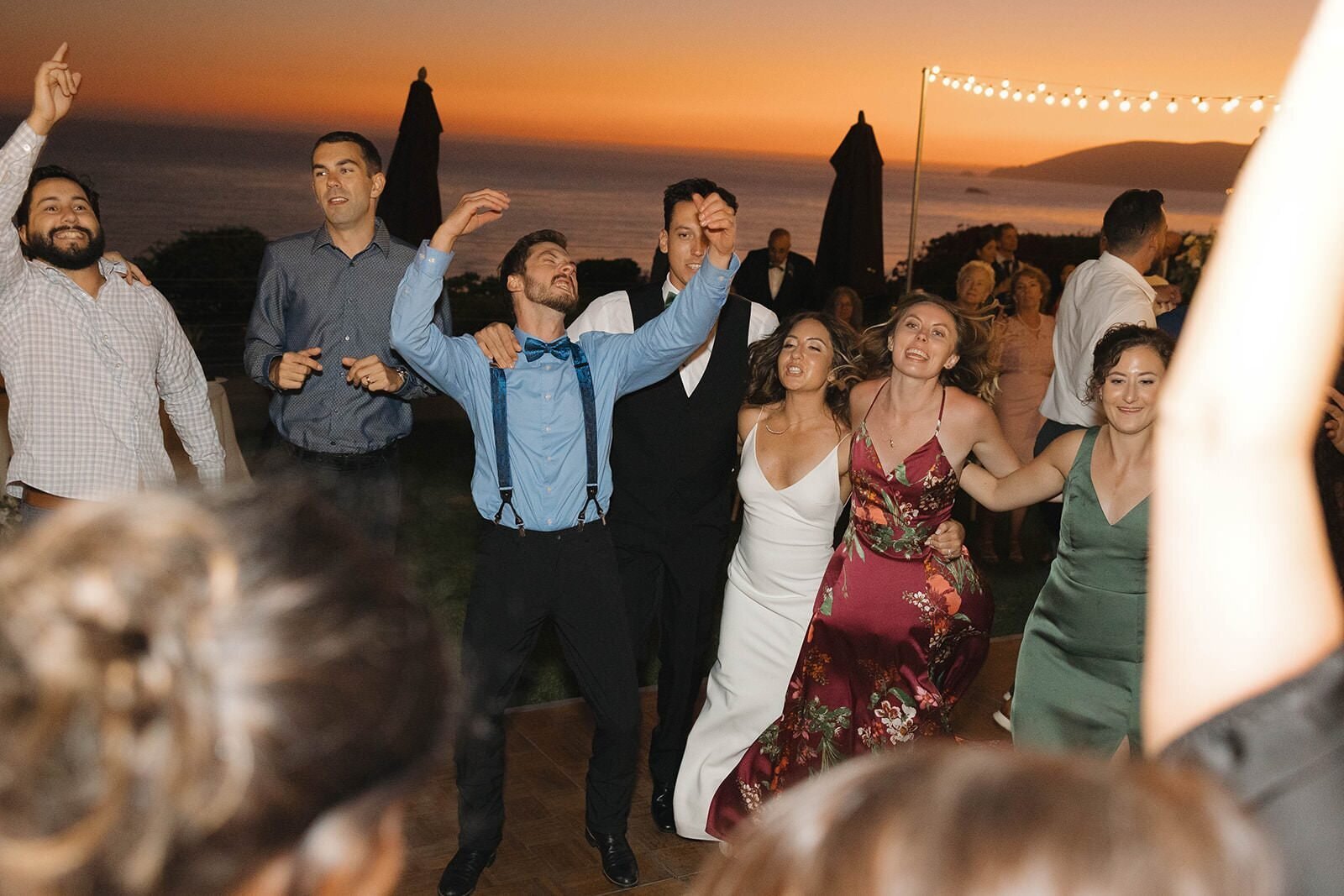 Guests dancing at sunset over the Pacific Ocean