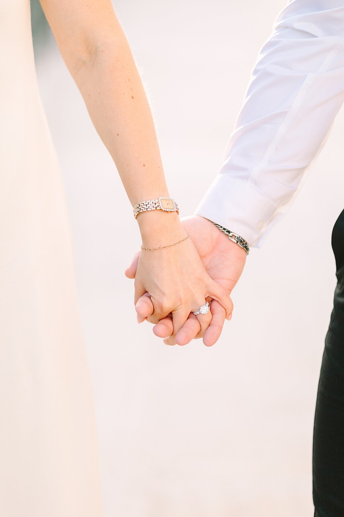 Couple holding hands and showing off the diamond engagement ring.