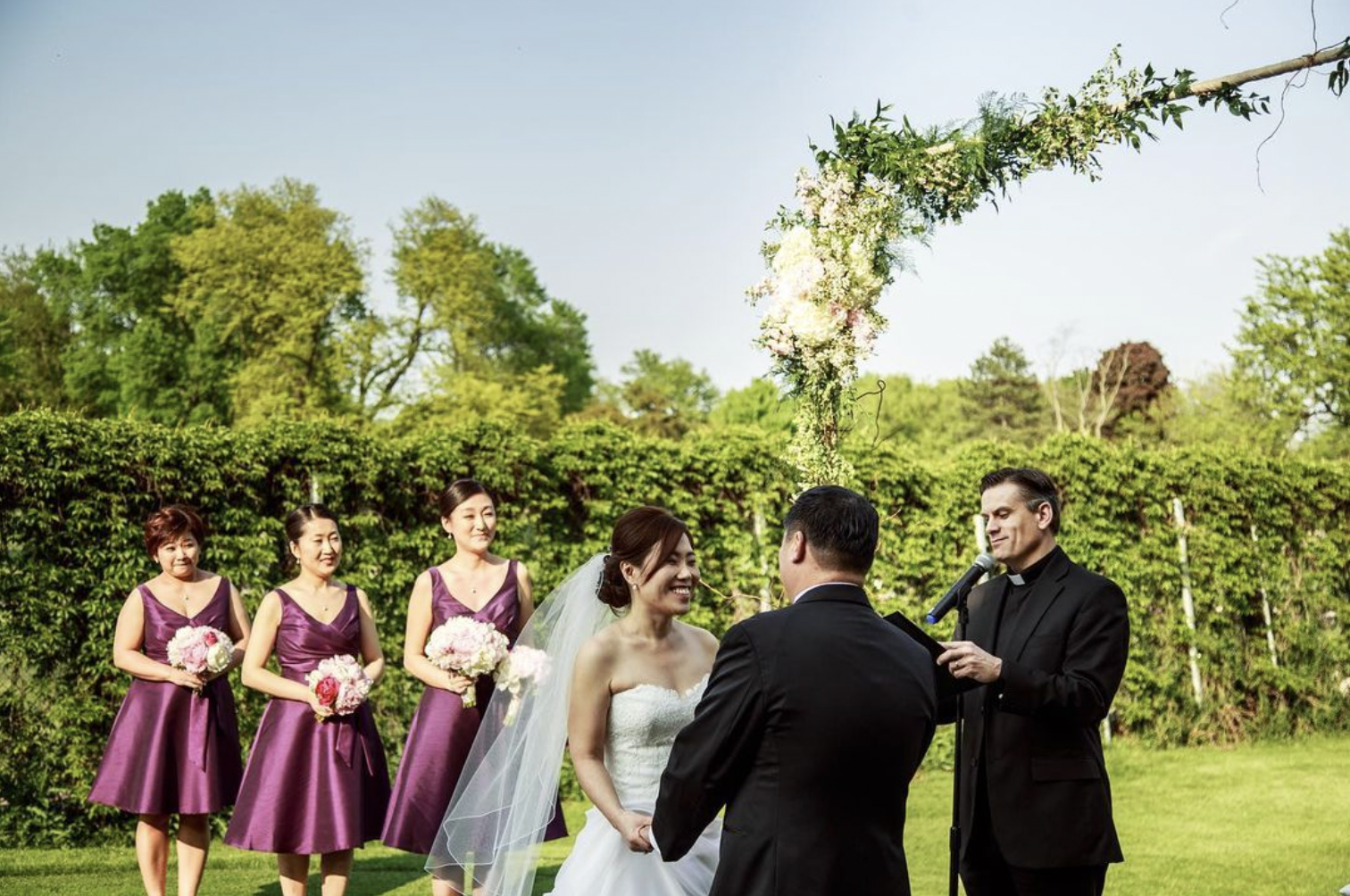 Bride and groom smile and hold hands during outdoor wedding ceremony