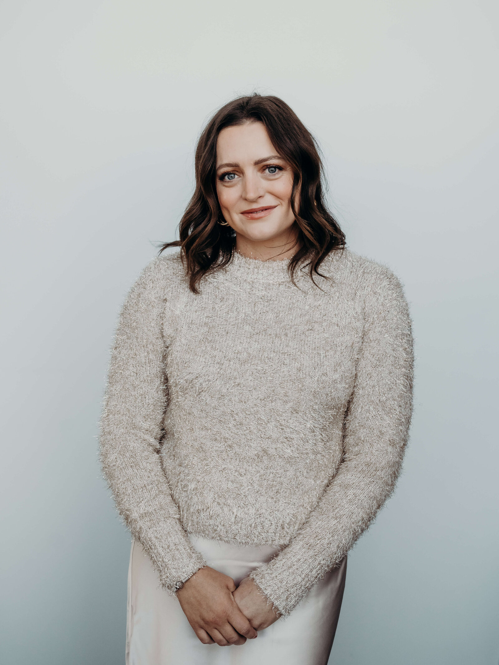 A branding headshot of a gorgeous woman, wearing a fluffy cream, colored sweater and a.
