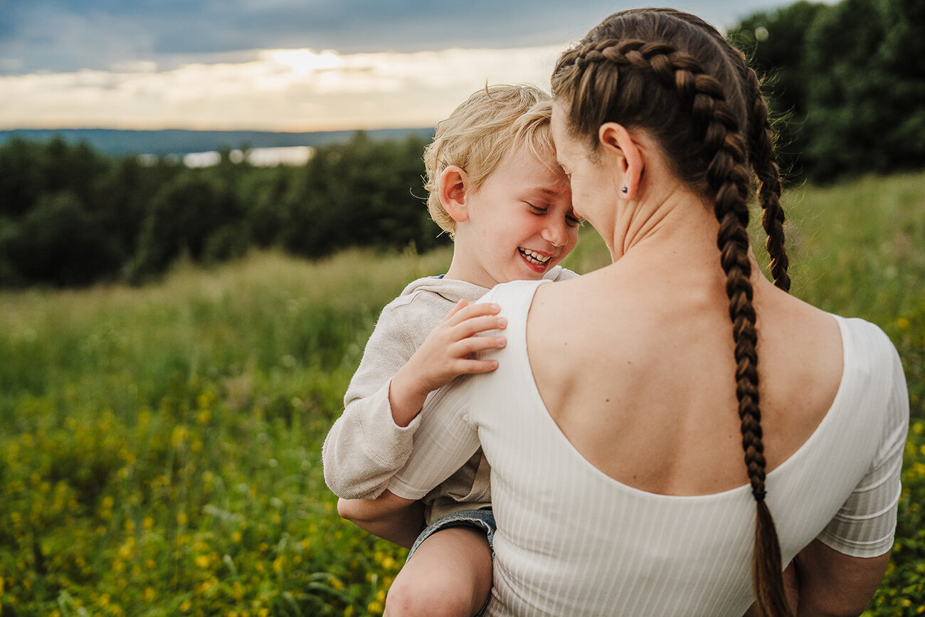 mom stands forehead to forehead with son in field of flowers
