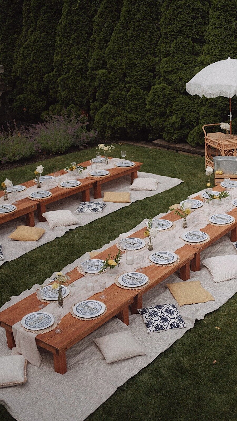Backyard picnic-style celebration with wooden low tables, patterned plates, and cozy cushions, styled by Yours Truly, a wedding planner and designer in New Jersey.