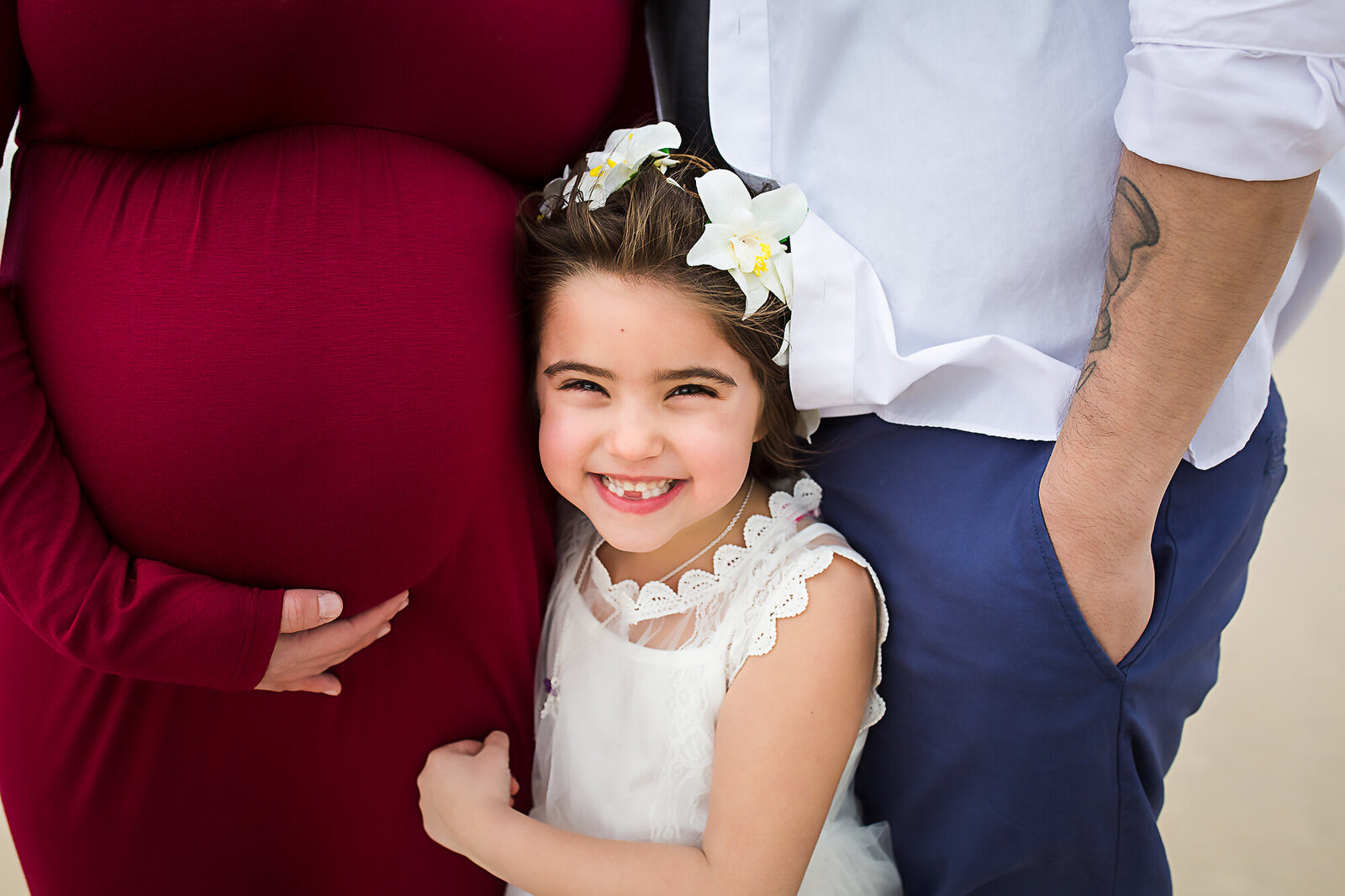 little girl smiling at camera next to moms pregnant belly by PHILADELPHIA MATERNITY PHOTOGRAPHER