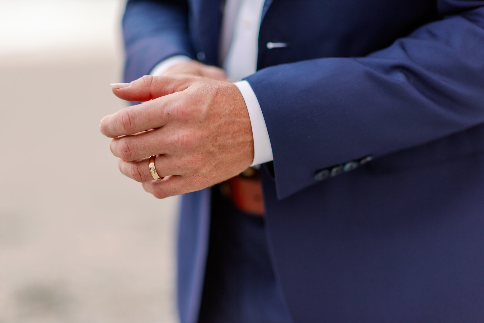 close up of grooms left hand, showing his wedding ring on his finger