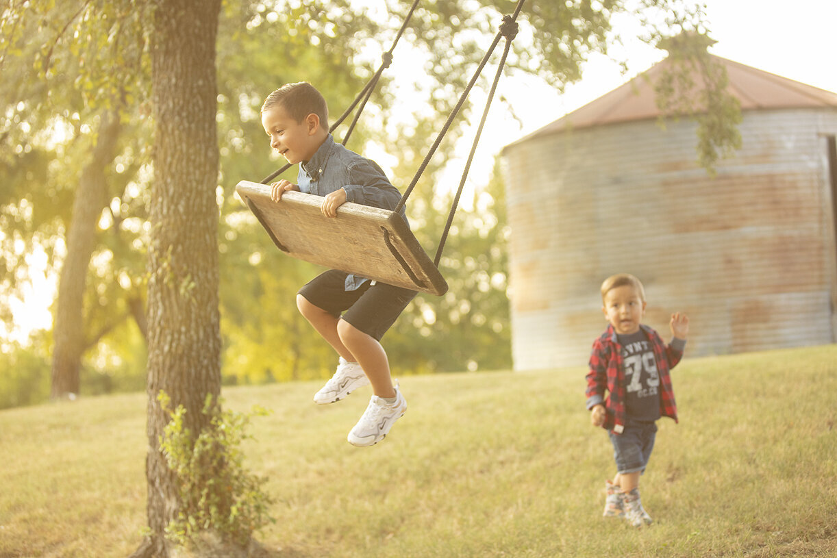 Brothers playing on swing during family photoshoot.