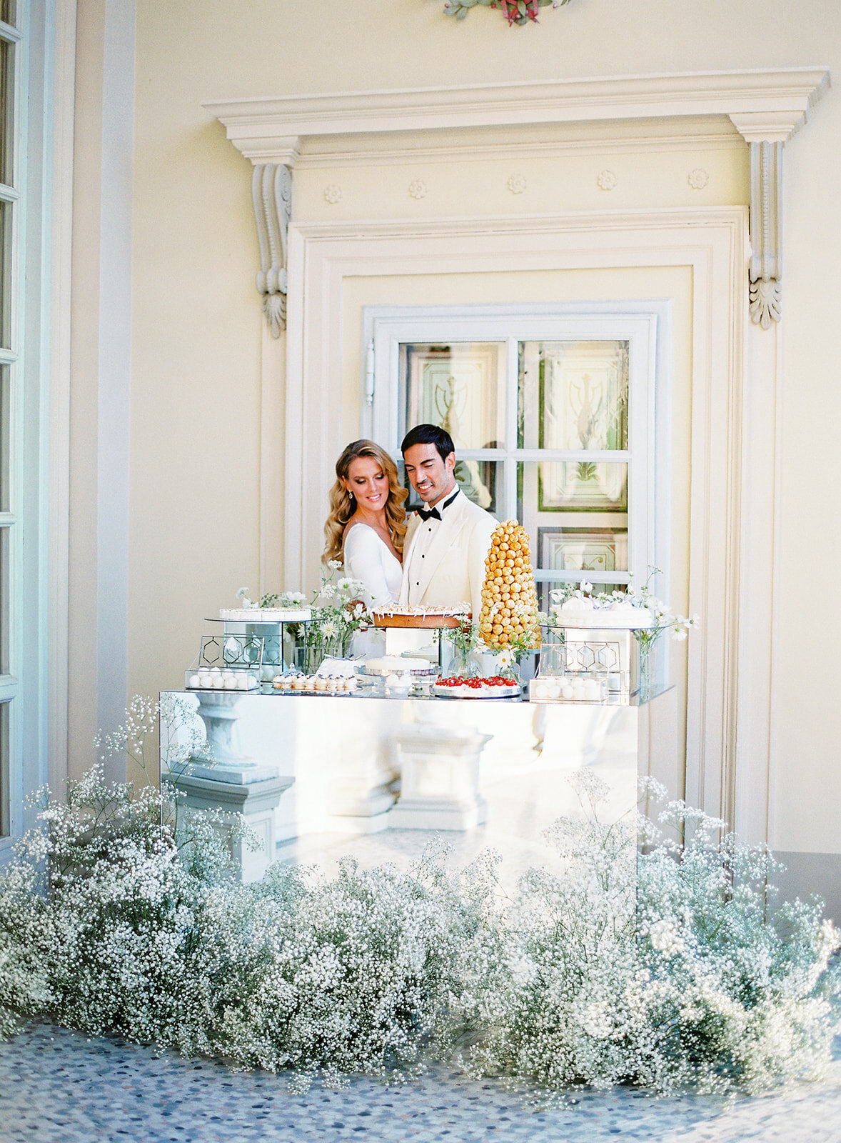 Bride and groom standing behind the dessert table Photographed by Italy wedding photographer Amy Mulder Photography