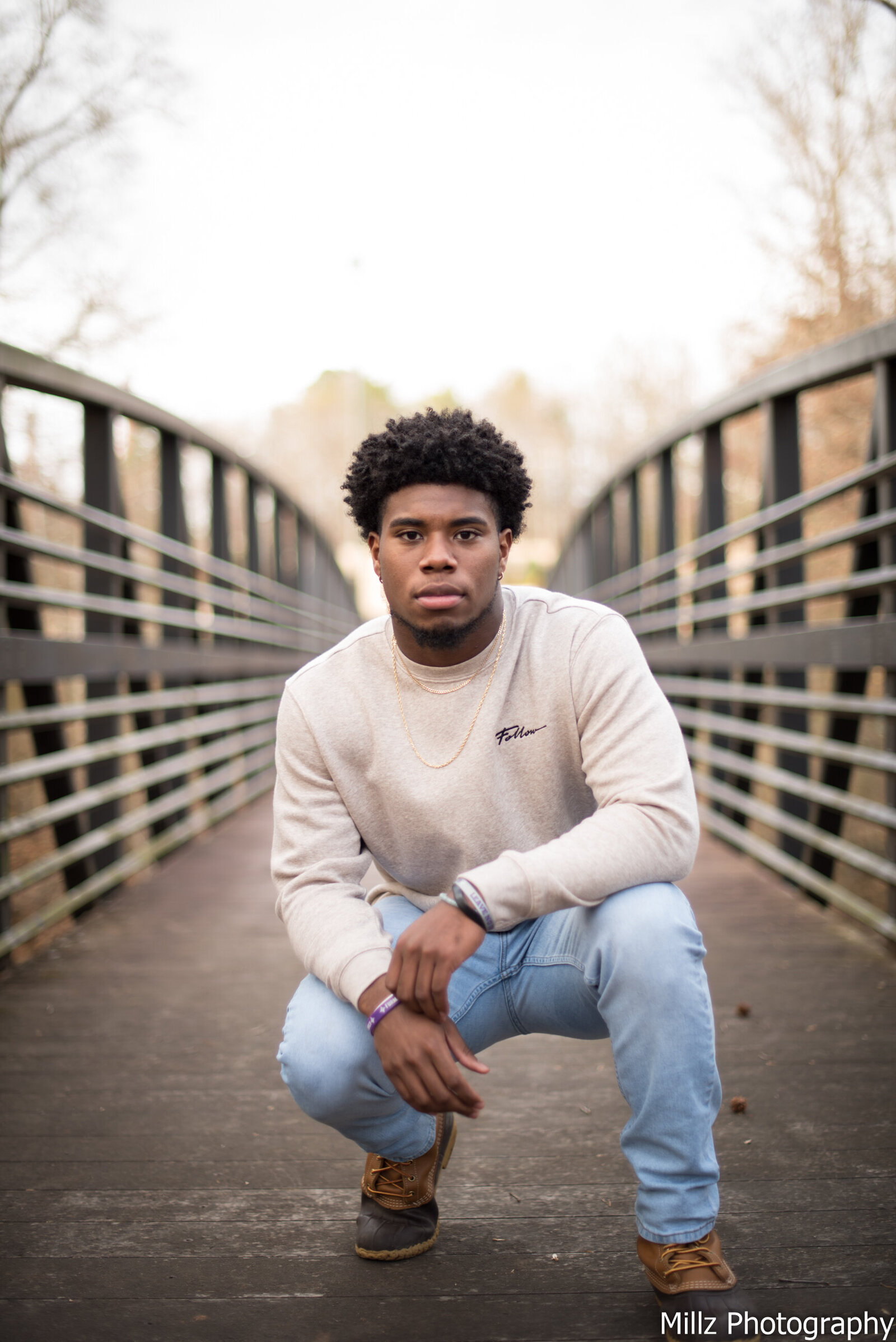 a high school senior posing for a photo on a bridge. photographed by Millz Photography in Greenville, SC