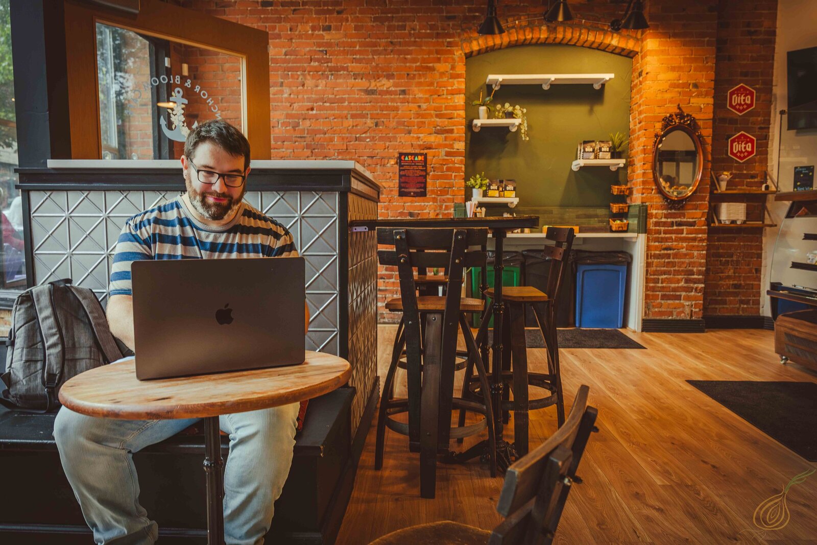 A man at a table, at a local coffee shop, working on his laptop, deeply engaged in his tasks or research.
