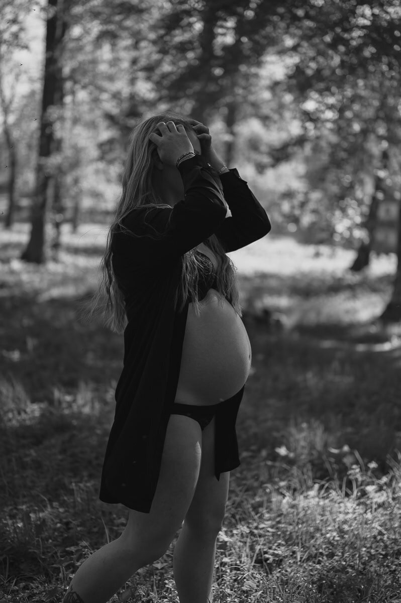 Gravid kvinna har öppen skjorta och underkläder och den gravida magen syns.