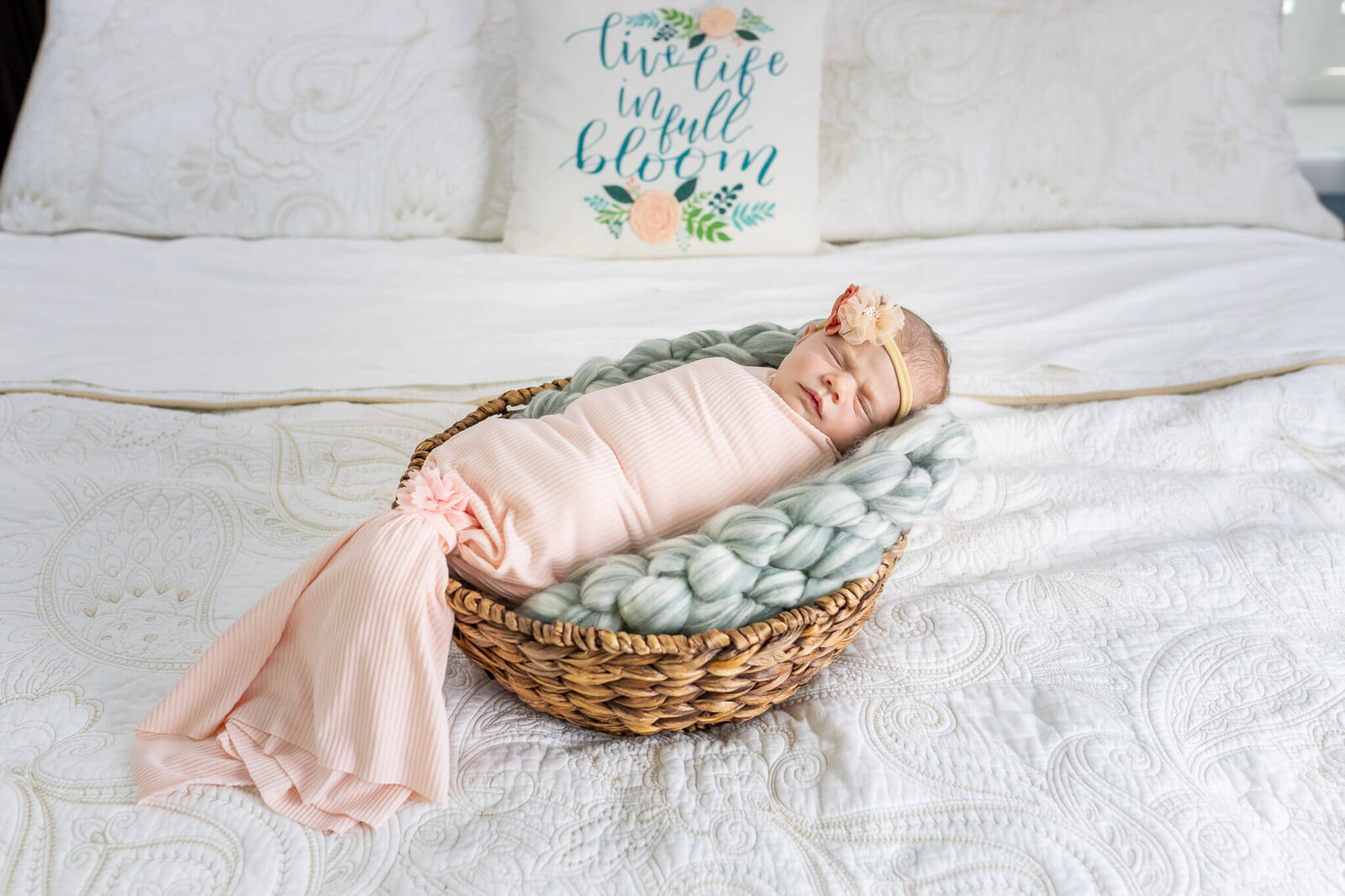 An Alexandria newborn girl posed in a basket on her parents' bed.
