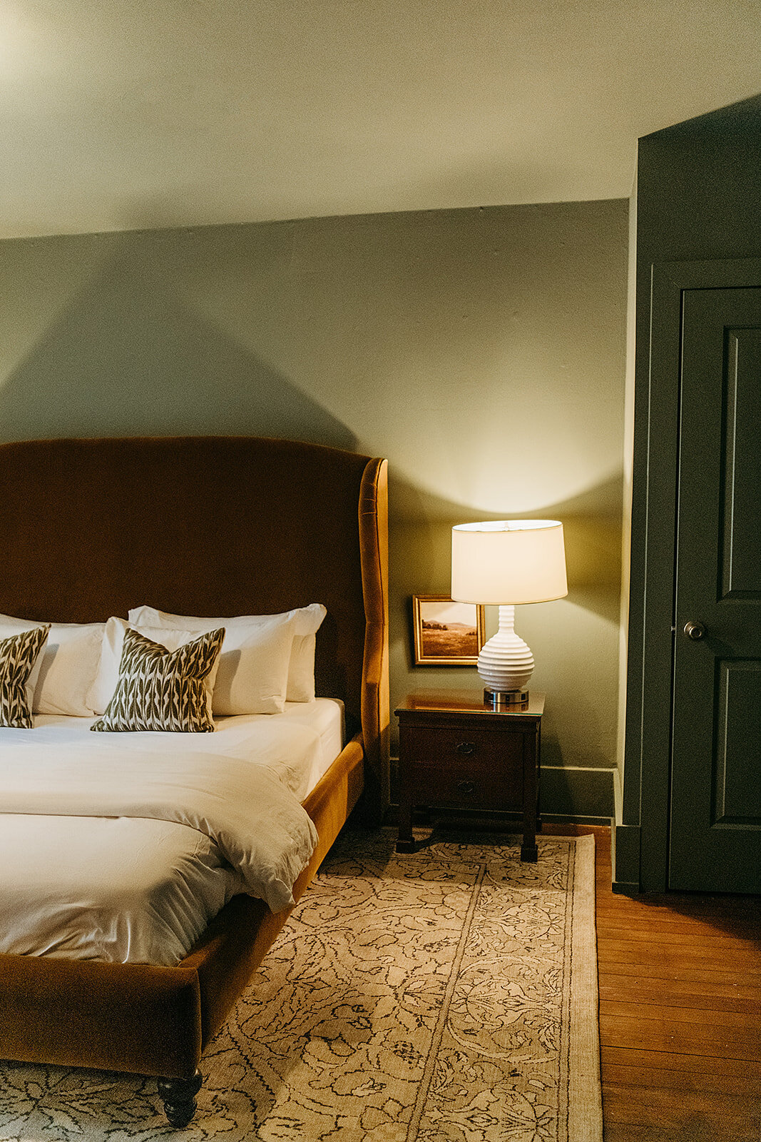 The Colorado King Room is so cozy with it's sage green walls and caramel velvet headboard