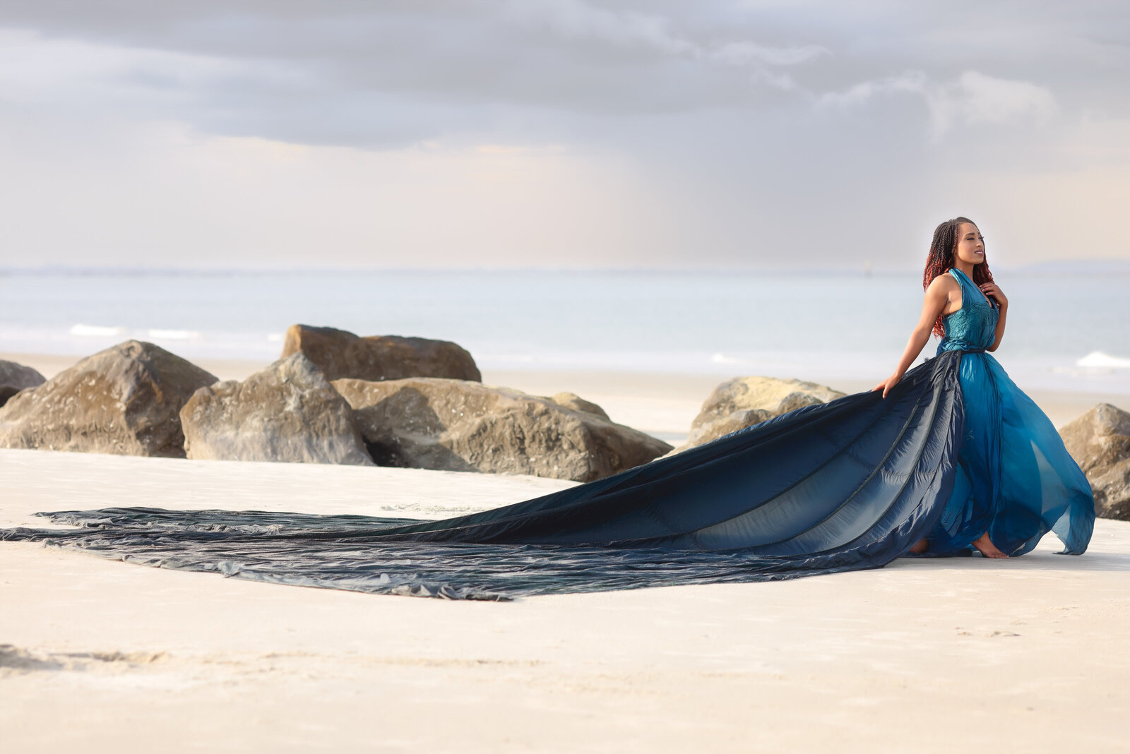 Savannah Boudoir Photography and Glamour showcases gorgeous black woman in blue parachute designer glamour gown on Tybee beach looking away