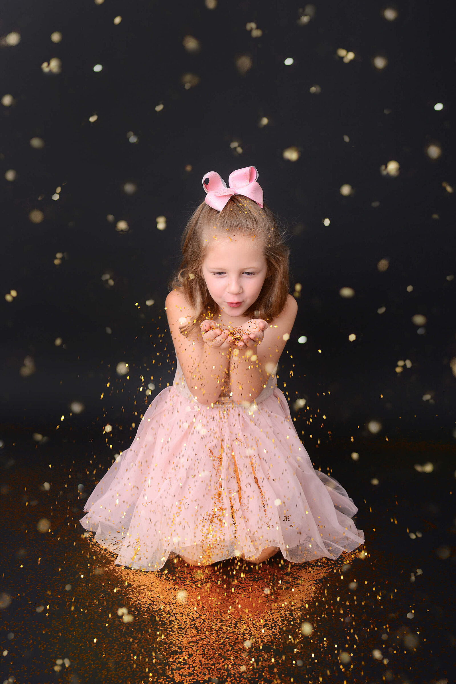girl blows glitter in the air at her glitter photo session
