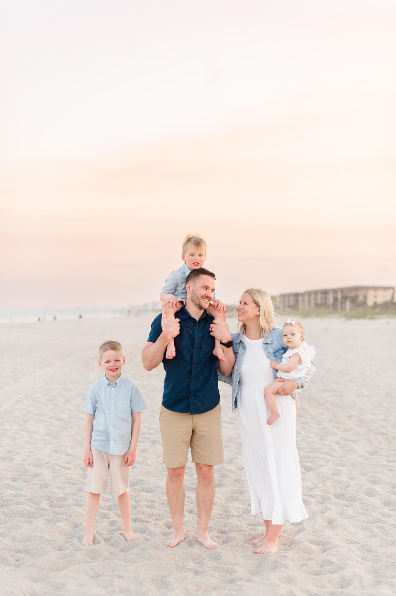 Family of five walking along the beach wearing blues for their family photos