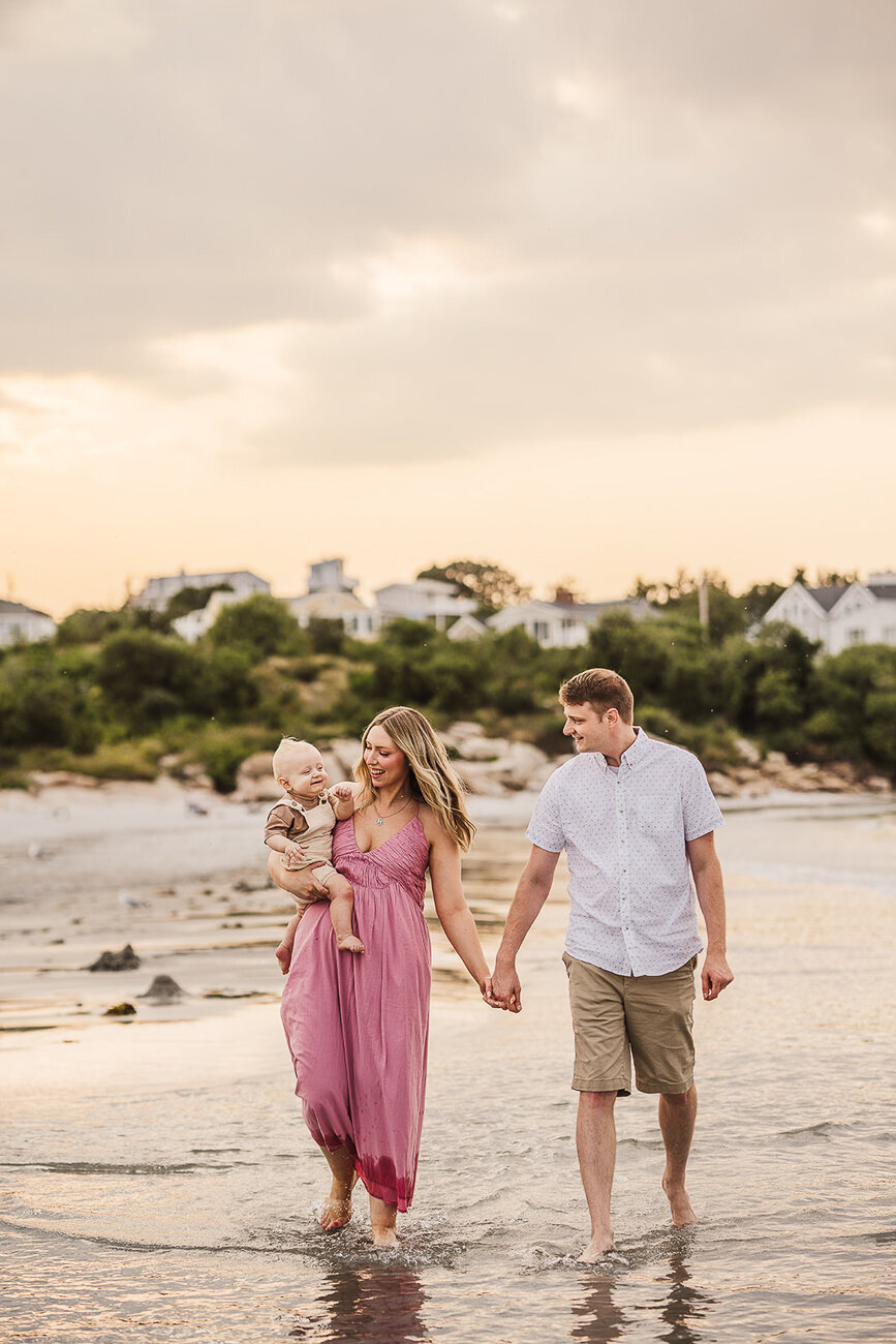 couple walks holding hands on boston beach with baby son