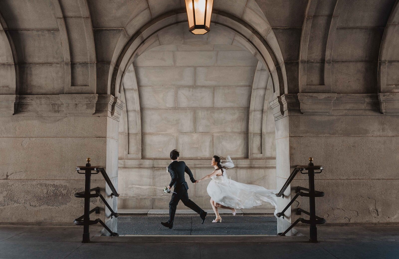 wedding couple running under an arch at library of congress in Washington D.C.