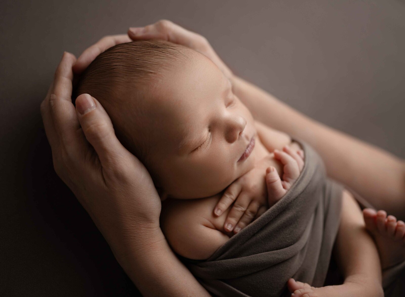 Baby sleeping peacefully in mom's hands. Photographed at Atlanta Newborn Photo studio.