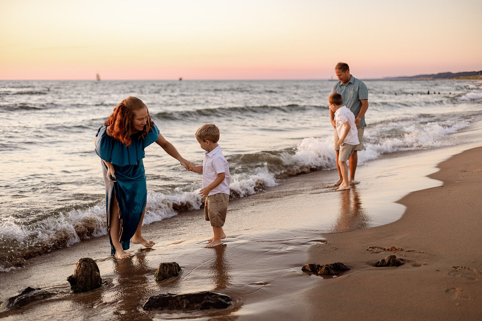A mother in a flowing green dress holding hands with her young son as they run through an open field in Grand Rapids, Michigan, capturing a joyful and playful moment.
