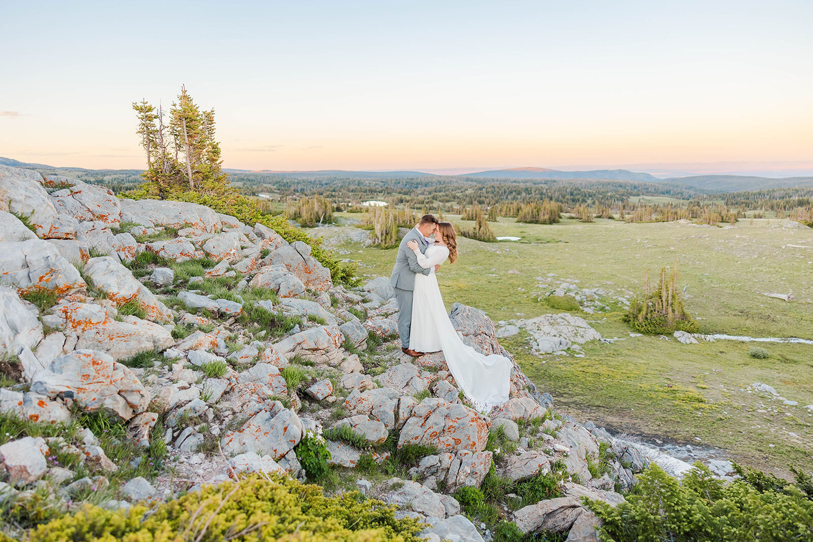 Bride and groom eloping in the breathtaking Snowy Range Mountains of Laramie, Wyoming, beneath stunning cotton candy skies, celebrating their love in a picturesque setting.