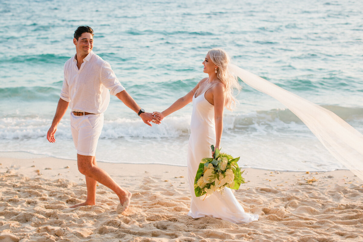 Bride and groom walking along the beach hand in hand