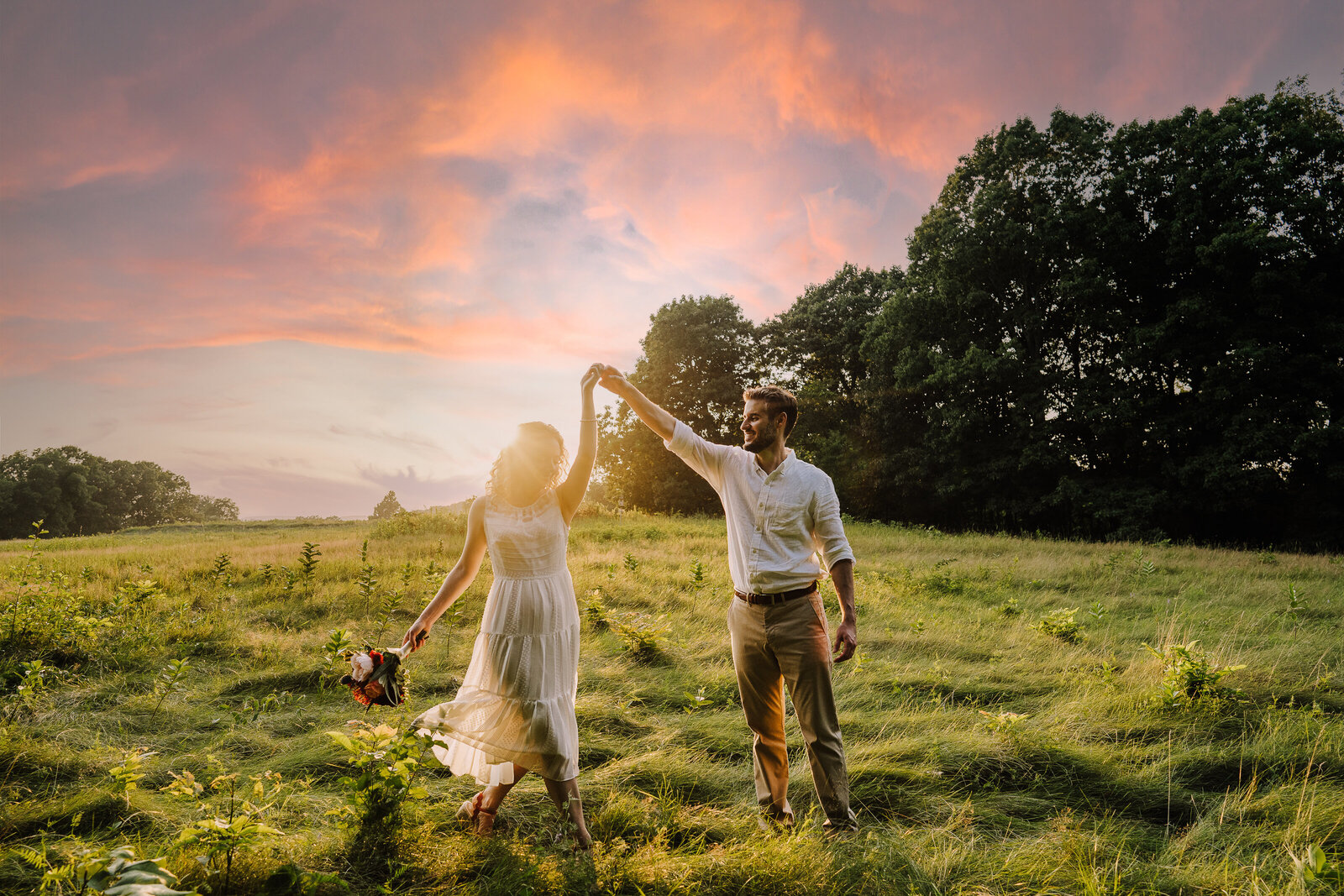 couple dances in field at sunset