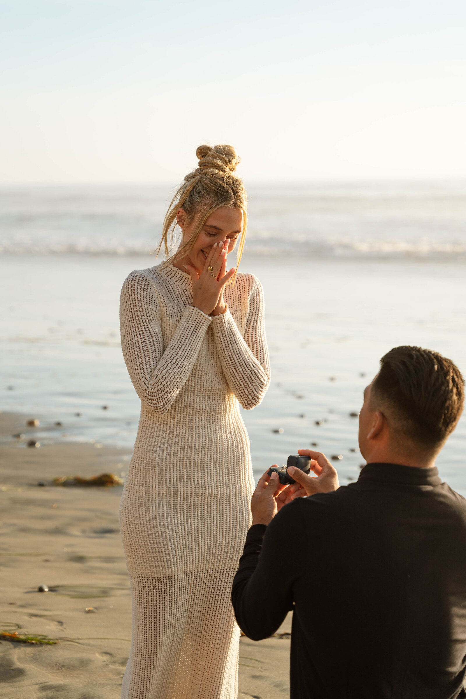 a woman getting proposed to on the beach 