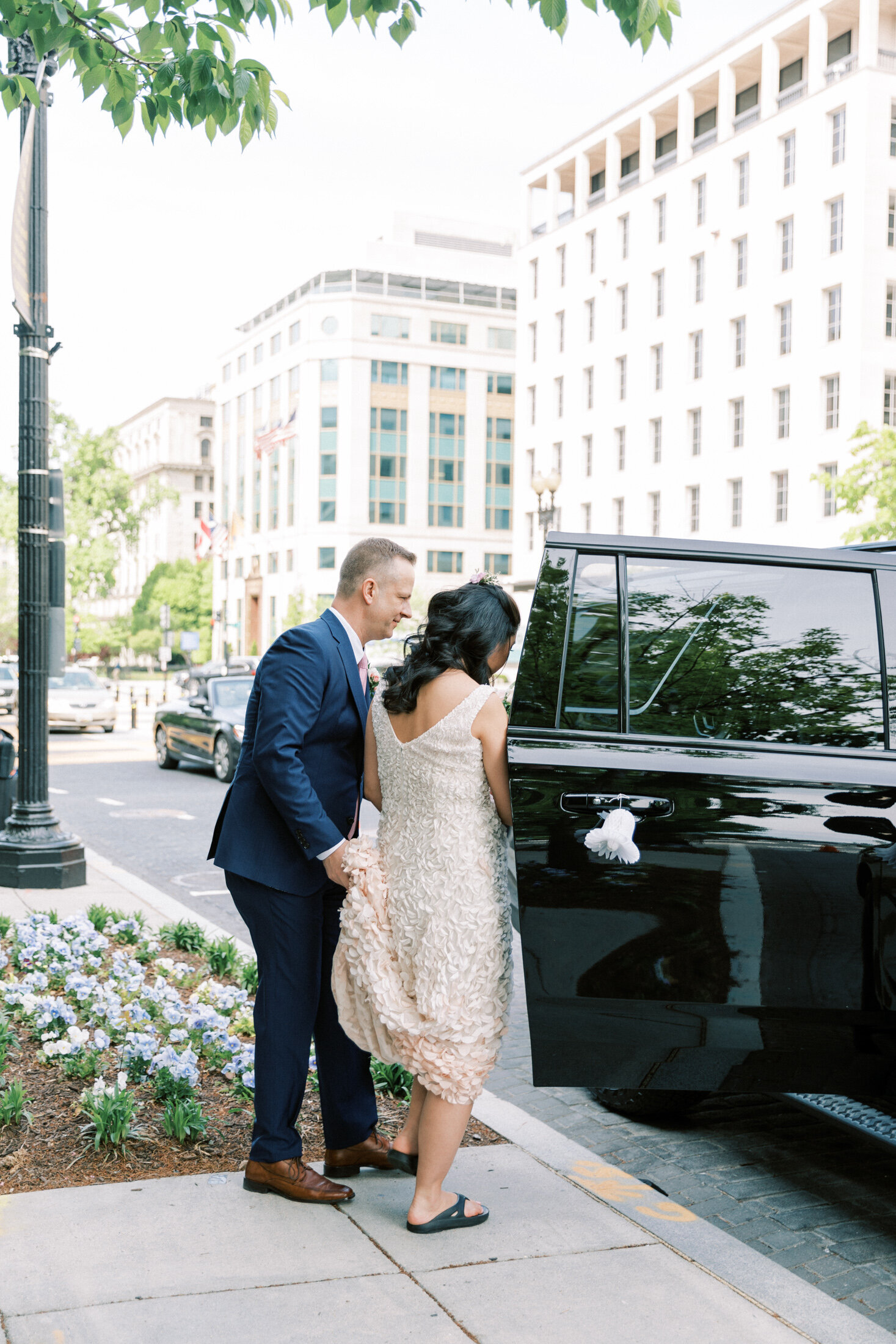 Groom helps bride get into their drivers SUV in DC